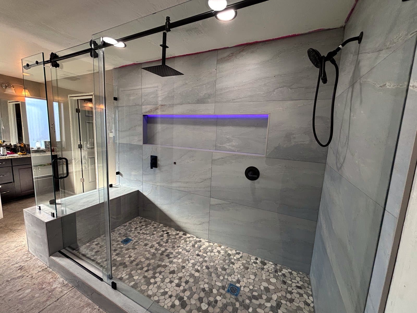 Frameless glass shower enclosure over a pebble-tile floor