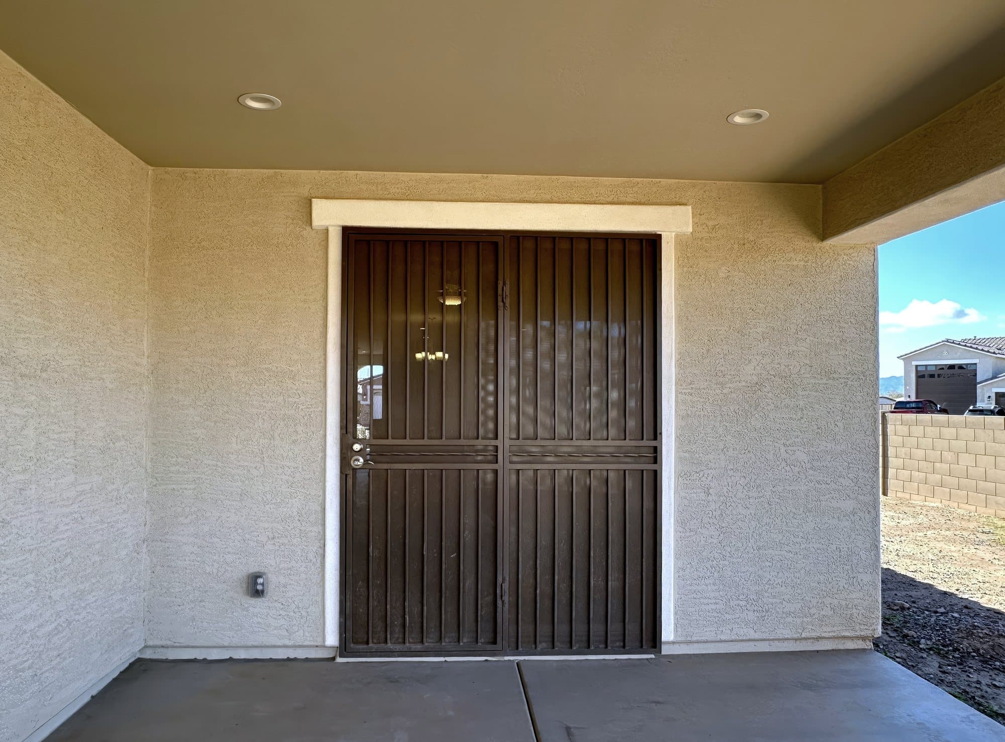 Bronze double steel security door installed at a covered entry