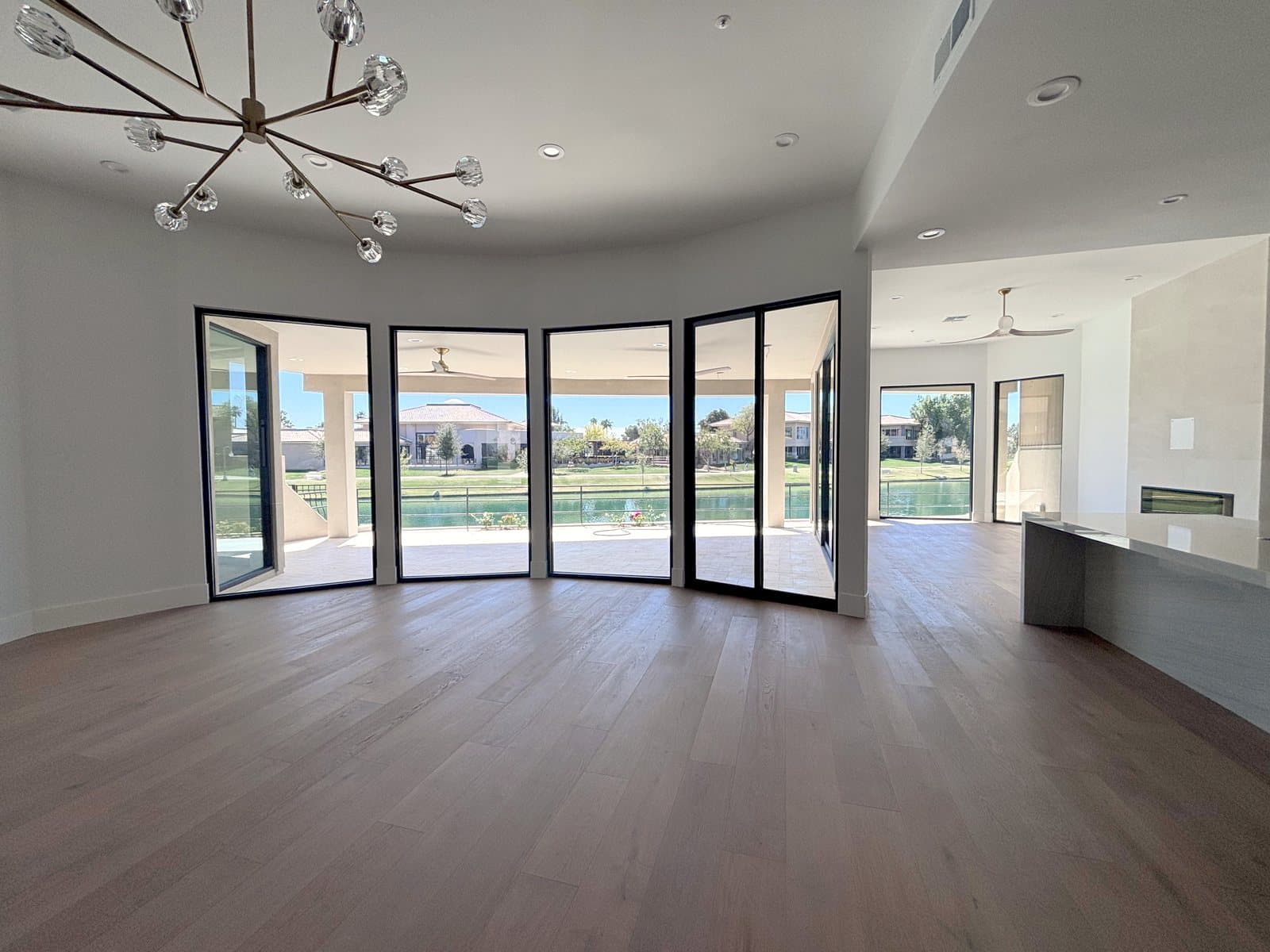 Curved run of black-framed sliding glass doors facing a lake